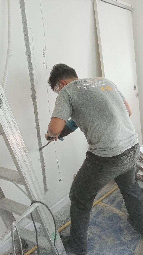 A technician is chiseling a wall to install electrical conduit.